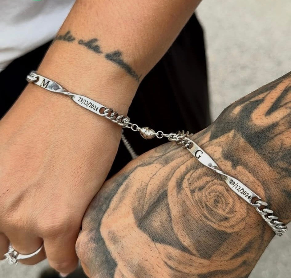 Bracciali Sempre Insieme color argento con iniziali e data, esposti con i due mezzi cuori uniti.